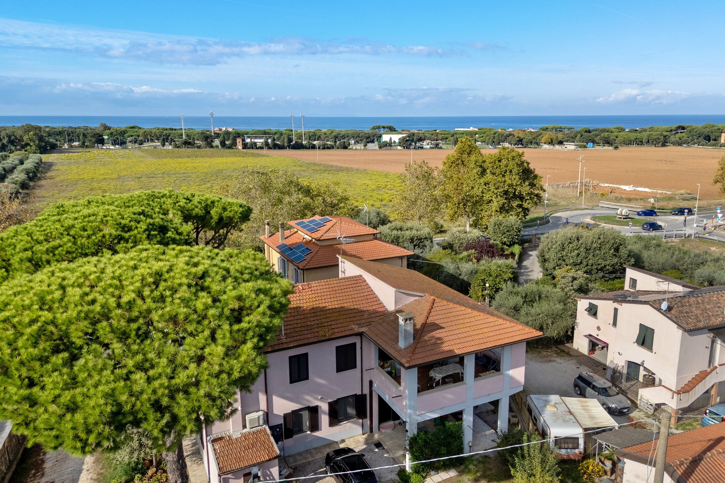 A residential area with houses, a vineyard, and a clear view of the sea.