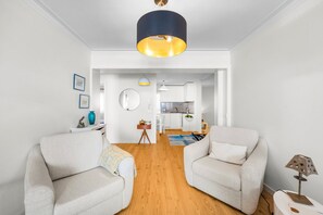 Una sala de estar moderna con dos sofás, una mesa de centro y un comedor con una cocina al fondo.