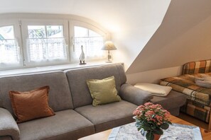 A cozy living room with a sofa, cushions, a table with a vase, and a lamp. - Taun coupling current (Born a. Darß)