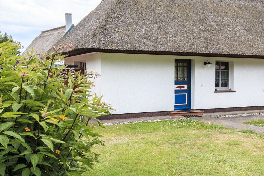 A traditional thatched-roof house with a white exterior and a blue door.