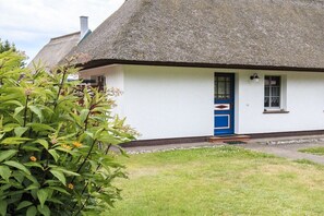 A traditional thatched-roof house with a white exterior and a blue door. - Taun coupling current (Born a. Darß)
