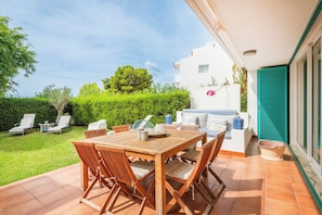 A patio with a wooden table and chairs, a barbecue grill, and a view of a white building with a green shutter. - Sunny 3BR Villa Prainha Clubhouse (Portimão)