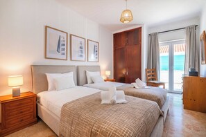 Ein Hotelzimmer mit zwei Betten, einem Schrank, einem Schreibtisch und Meerblick.
