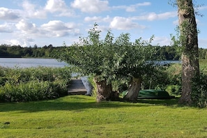 A grassy area with a tree and a dock extending into a body of water. - with direct lake access (Trams)