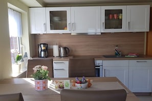 A compact kitchen with white cabinets, a coffee maker, a kettle, and a sink. - with direct lake access (Trams)