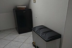 A compact kitchenette with a refrigerator and a trash bin. - Holiday apartment with 1 bedroom (Moisburg)