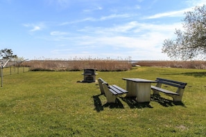 An outdoor area with a picnic table and benches, a fire pit, and a view of a natural landscape. - Holiday apartment with 2 bedrooms (Born a. Darß)