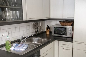 A kitchen with a microwave, sink, and utensils. - Holiday apartment with 2 bedrooms (Born a. Darß)