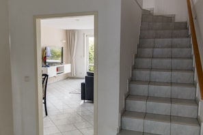 Eine Treppe führt zu einem Balkon mit Blick auf Grünflächen.