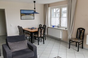 Ein Essbereich mit Tisch, Stühlen und einem fenster mit Vorhängen.