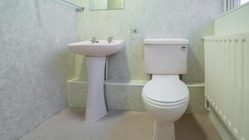 Un bagno con lavandino bianco, servizi igienici e cabina doccia in vetro.