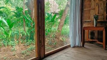 A room with a large window, wooden floor, and a small table with a plant.