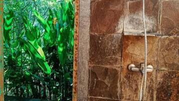 A shower area with a stone wall and a showerhead.