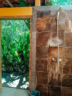 Un área de ducha con pared de piedra y cabezal de ducha.