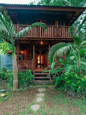 A wooden cabin with a balcony, surrounded by tropical vegetation. - Alaya Ecolodge (Buleleng)