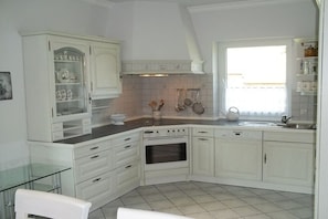 A kitchen with white cabinets, a built-in oven, and a window providing natural light. - Holiday apartment in Malkendorf with Wi-Fi (Malkendorf)