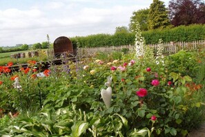A garden with a variety of flowers and a rustic wooden structure. - Holiday apartment in Malkendorf with Wi-Fi (Malkendorf)