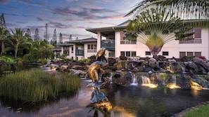 Um resort com lago, cascata e esculturas de golfinhos.