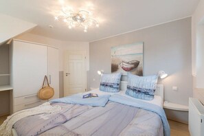 A bedroom with a bed, a nightstand, a lamp, a painting on the wall, and a wardrobe. - Caravel in Captain Parow (Zingst)