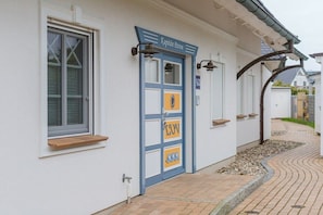 A building with a blue door labeled 'Kapitan Parow' and a window with a wooden shelf. - Caravel in Captain Parow (Zingst)