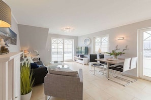 A modern living room with a sofa, coffee table, and dining area with chairs. - Caravel in Captain Parow (Zingst)