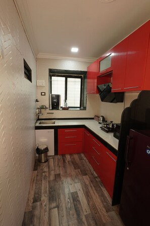 A compact kitchen with a window, a coffee machine, and a refrigerator. - Grace Stylish - Cozy 1-Bedroom Stay in Bandra West (Mumbai)