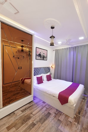 A modern bedroom with a bed, a mirror, a painting, and a ceiling fan. - Grace Stylish - Cozy 1-Bedroom Stay in Bandra West (Mumbai)