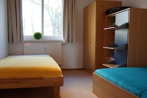 Ett sovrum med två sängar, en garderob och ett element.