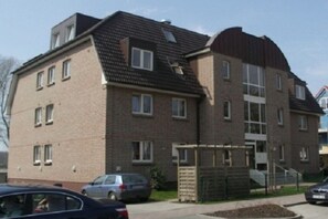 A multi-story residential building with a brick facade, a flat roof, and a gated entrance. - Holiday apartment with 2 bedrooms (Ostseebad Boltenhagen)