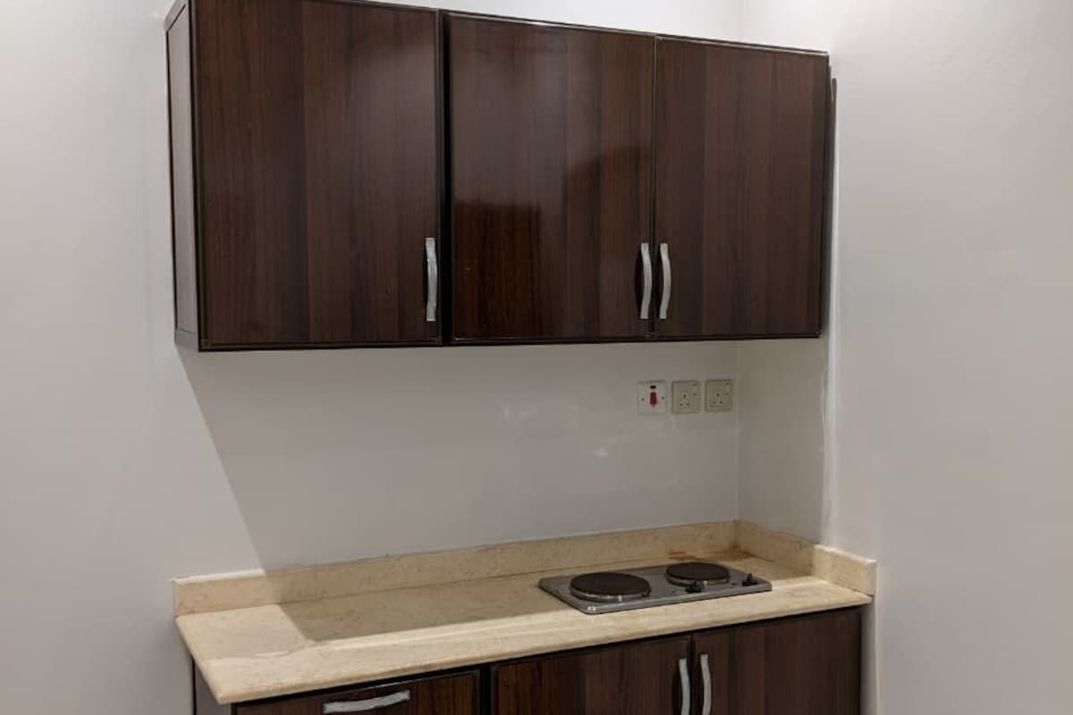 A kitchenette with dark wood cabinets, a white countertop, and a built-in stove.