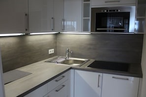 A modern kitchen with stainless steel appliances, a double sink, and white cabinetry. - Holiday apartment in Sylt with 2 bedrooms (Sylt \/ OT Westerland)