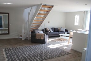A modern living room with a staircase, a sofa, a coffee table, and a small kitchen area. - Holiday apartment in Sylt with 1 bedroom (Sylt \/ OT Westerland)