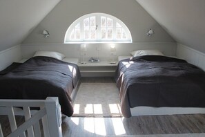 A bedroom with two beds, a window, and a white railing. - Holiday apartment in Sylt with 1 bedroom (Sylt \/ OT Westerland)