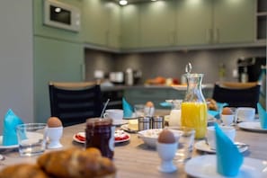 A breakfast setting with a table set for two, including plates, cups, and a bottle of orange juice. - Holiday home with 3 bedrooms (Ostseebad Zingst a Darß)