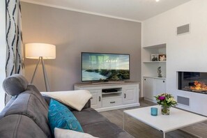 A modern living room with a flat-screen TV, a sofa, a coffee table, and a fireplace. - Holiday home with 3 bedrooms (Ostseebad Zingst a Darß)