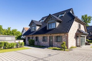 A two-story house with a sloped roof, brick exterior, and a paved driveway. - Holiday home with 3 bedrooms (Ostseebad Zingst a Darß)