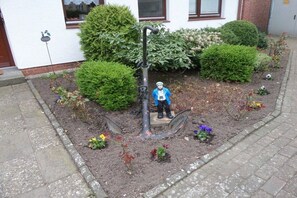 A garden with a sculpture of a figure holding a shovel, surrounded by various plants and flowers. - Apartment in Norderstedt with swimming pool (Norderstedt)