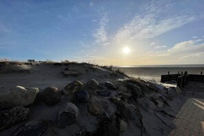 A beach with a wooden fence, a paved walkway, and a clear sky. - Holiday apartment with 1 bedroom (Burgtiefe auf Fehmarn)