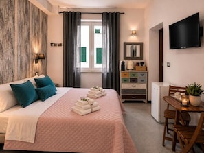 Ein Hotelzimmer mit einem Bett, einem Schreibtisch, einem Fernseher und einem kleinen Kühlschrank.