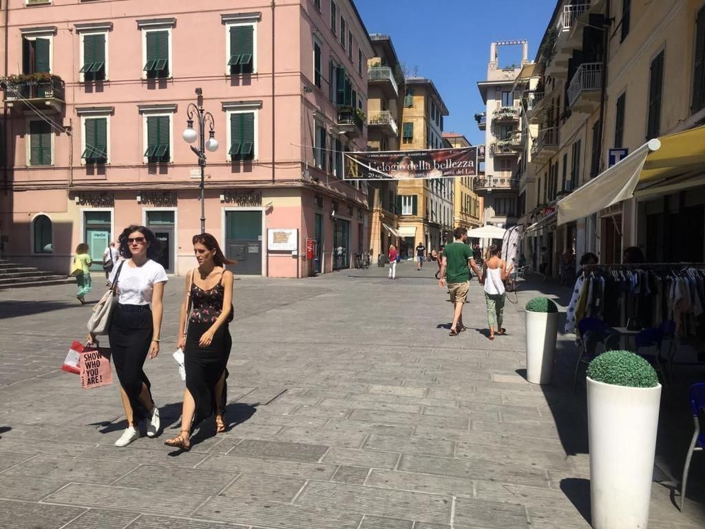 A pedestrian street with buildings, shops, and outdoor seating areas.