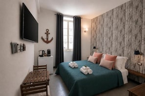 Ein Hotelzimmer mit Bett, Schreibtisch, Stuhl, Fernseher, einem Fenster mit Vorhängen und einer Wandleuchte.