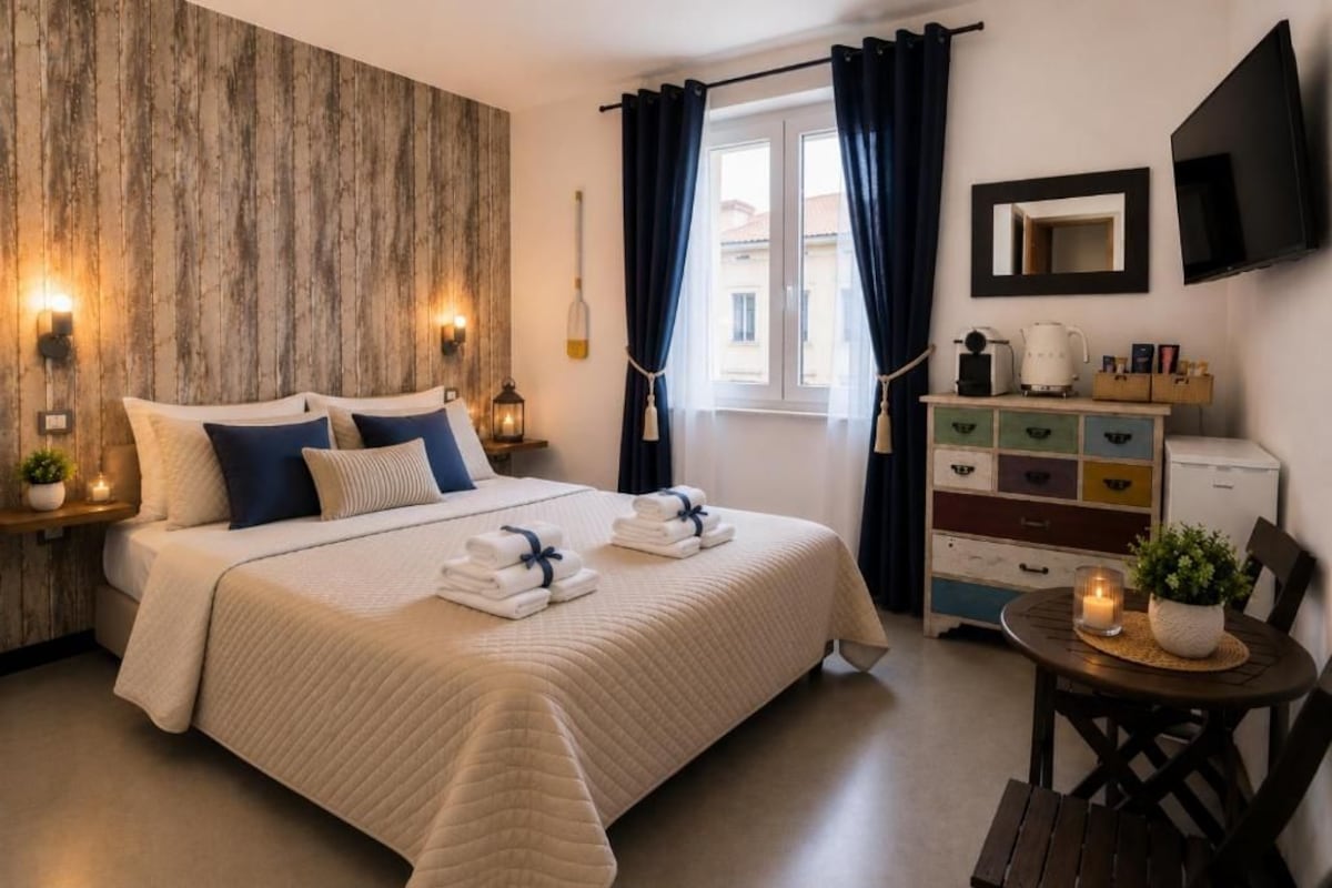 Ein Hotelzimmer mit einem Bett, Nachttischen, einem Schminktisch, einem Fernseher und einem Fenster mit Vorhängen.