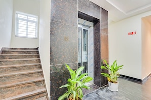 A hotel entrance with a marble staircase, a fire exit sign, and potted plants. - Townhouse Sri Nirvana Grand (Hyderabad)