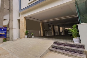 A hotel entrance with a covered driveway, potted plants, and a signboard. - Townhouse Sri Nirvana Grand (Hyderabad)