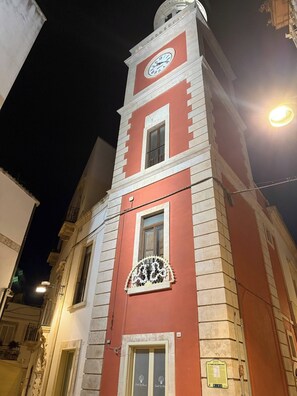 A building with a clock tower, a balcony with ornate railings, and a sign indicating a restaurant. - Historic Stone Vault in Noci Incl Breakfast (Noci)