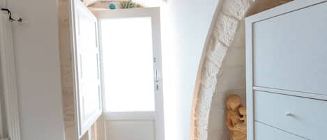 A room with a white door, a stone wall, and a statue.