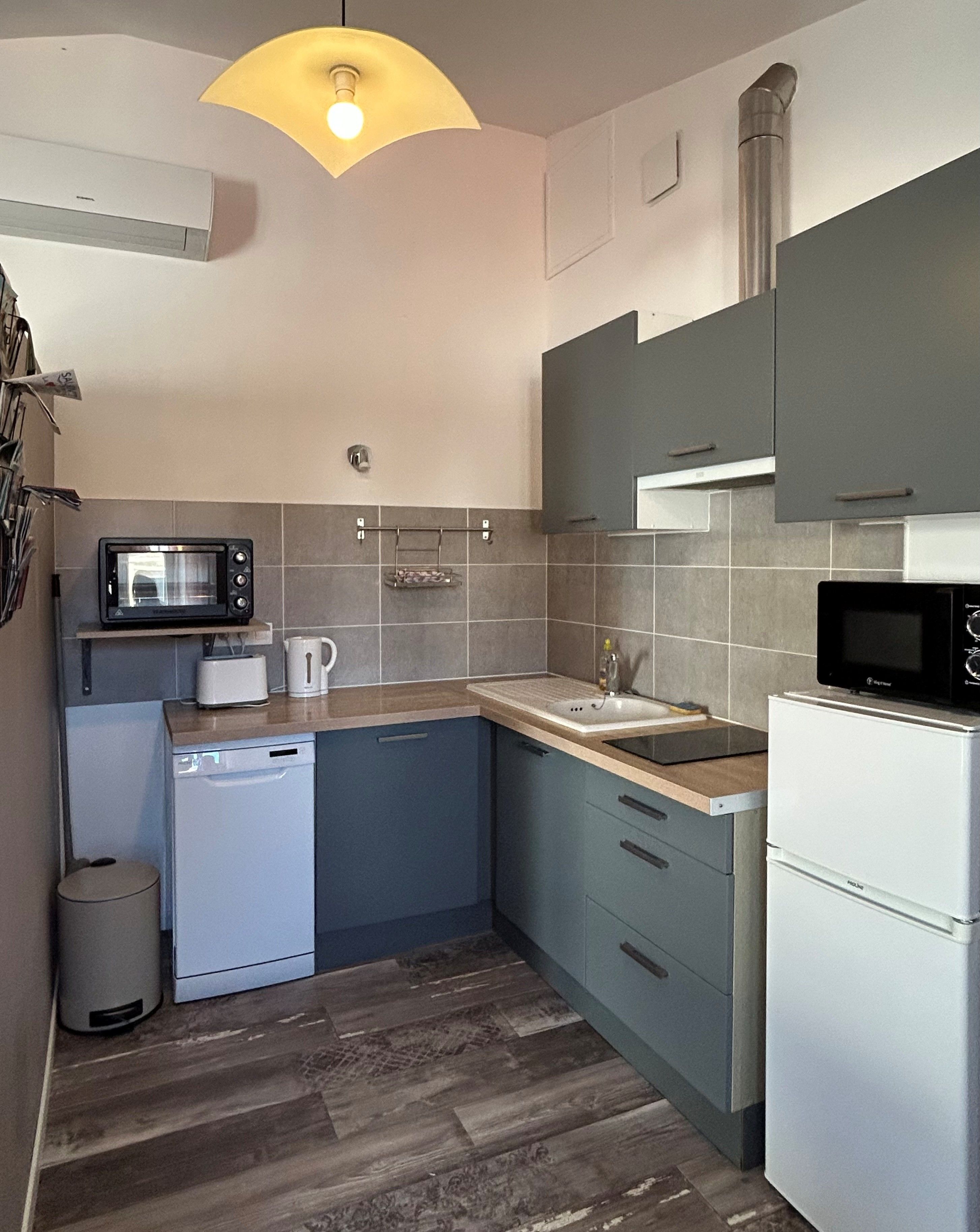 A compact kitchen with a microwave, toaster, sink, and dishwasher.