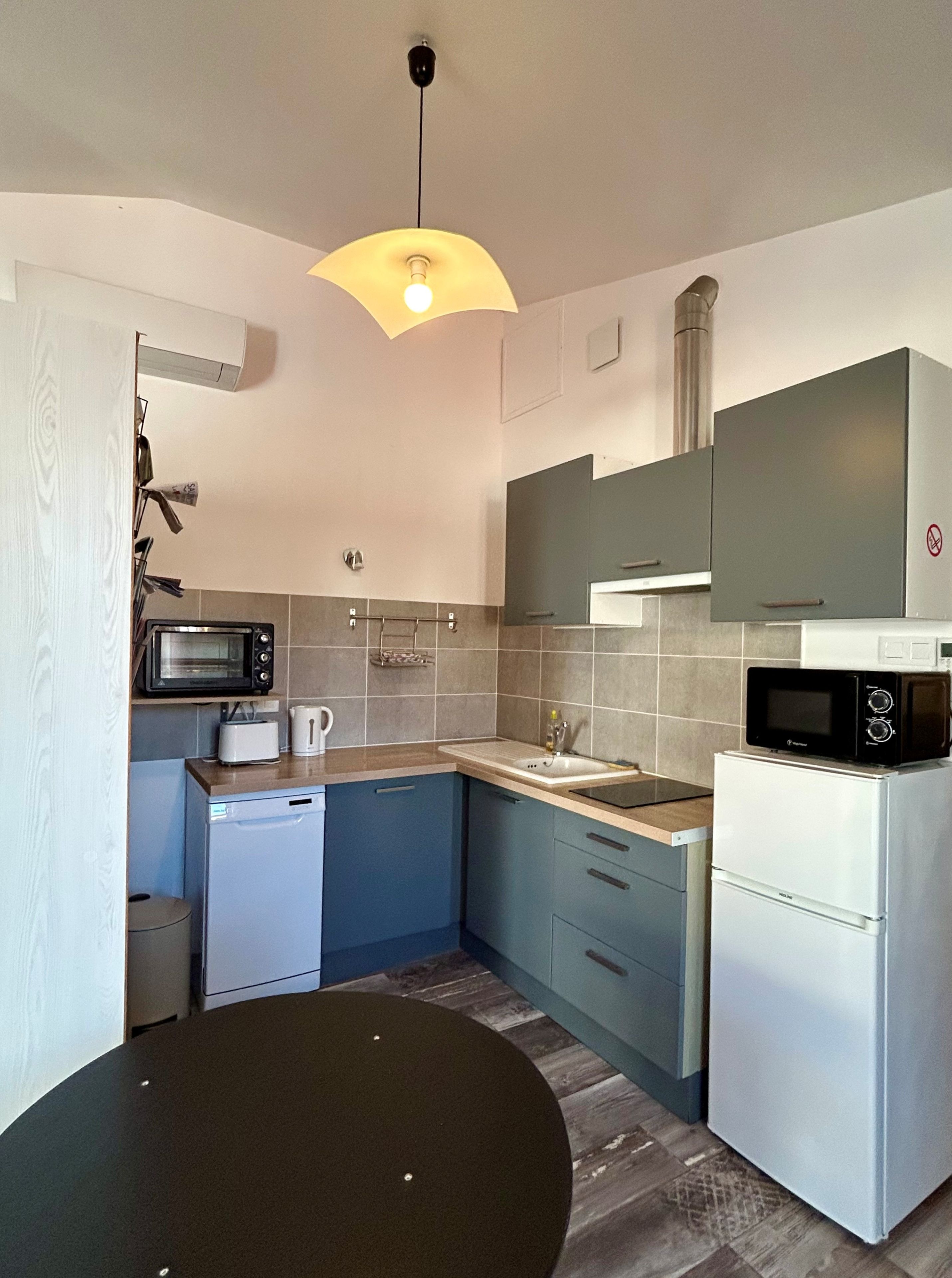 Una cocina compacta equipada con microondas, tostadora, fregadero y un refrigerador pequeño.