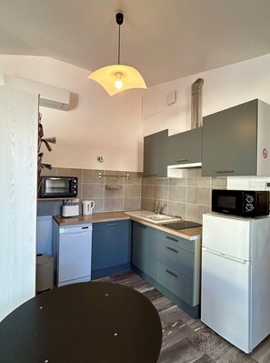 Una cocina compacta equipada con microondas, tostadora, fregadero y un refrigerador pequeño.