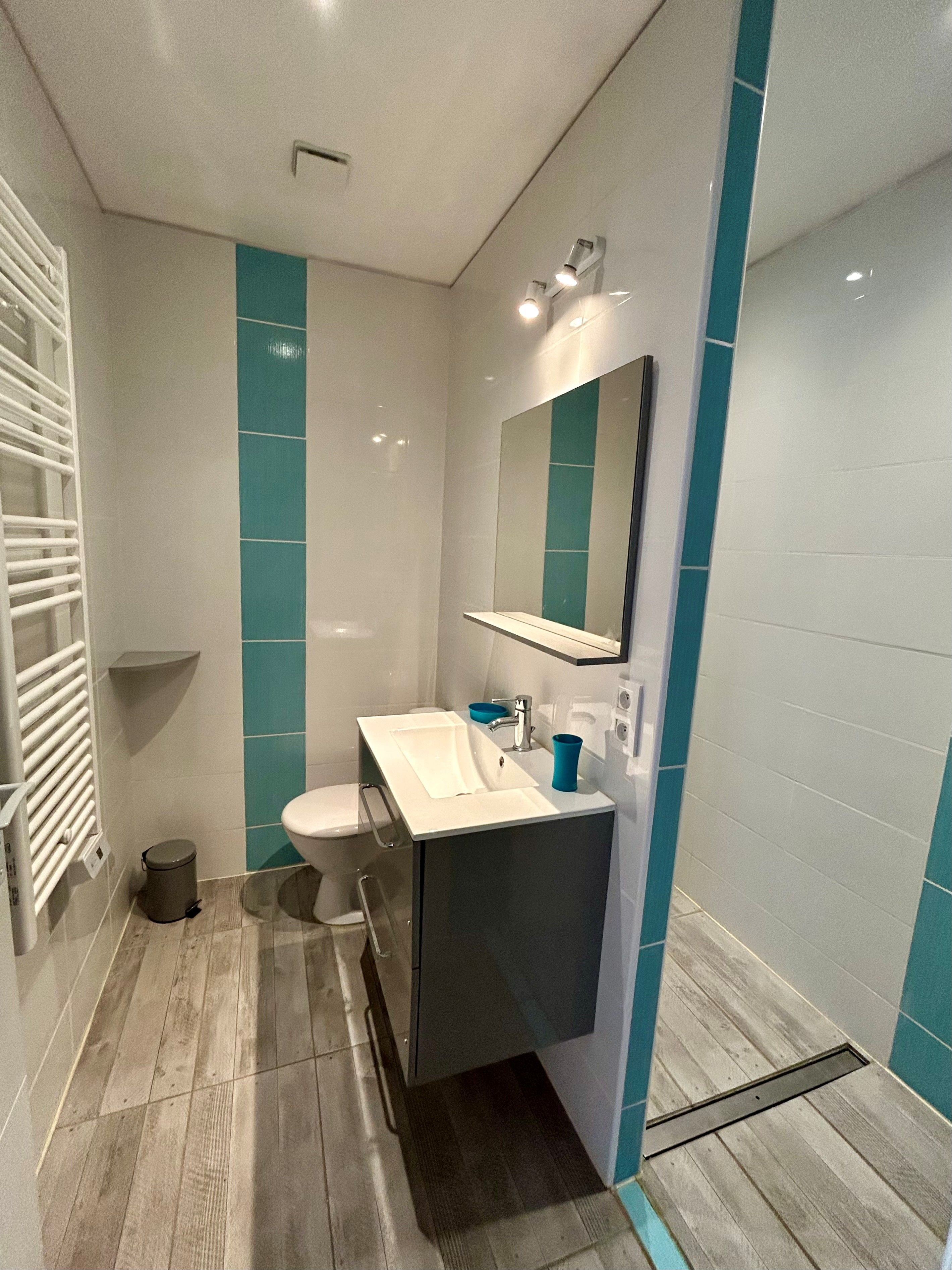 A modern bathroom with a white sink, a mirror, and a toilet.